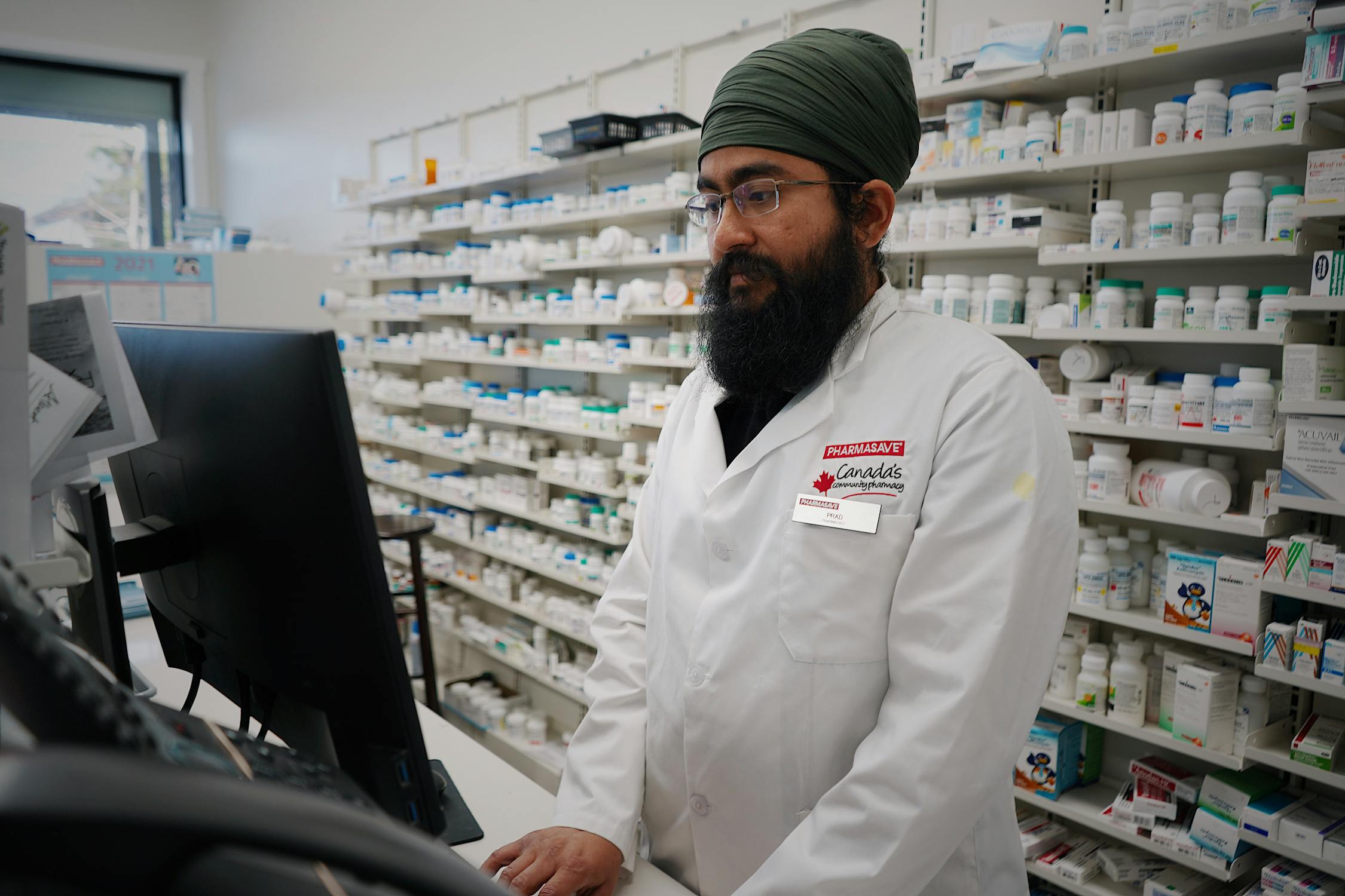 Pharmacist standing behind the pharmacy counter ready to assist patients