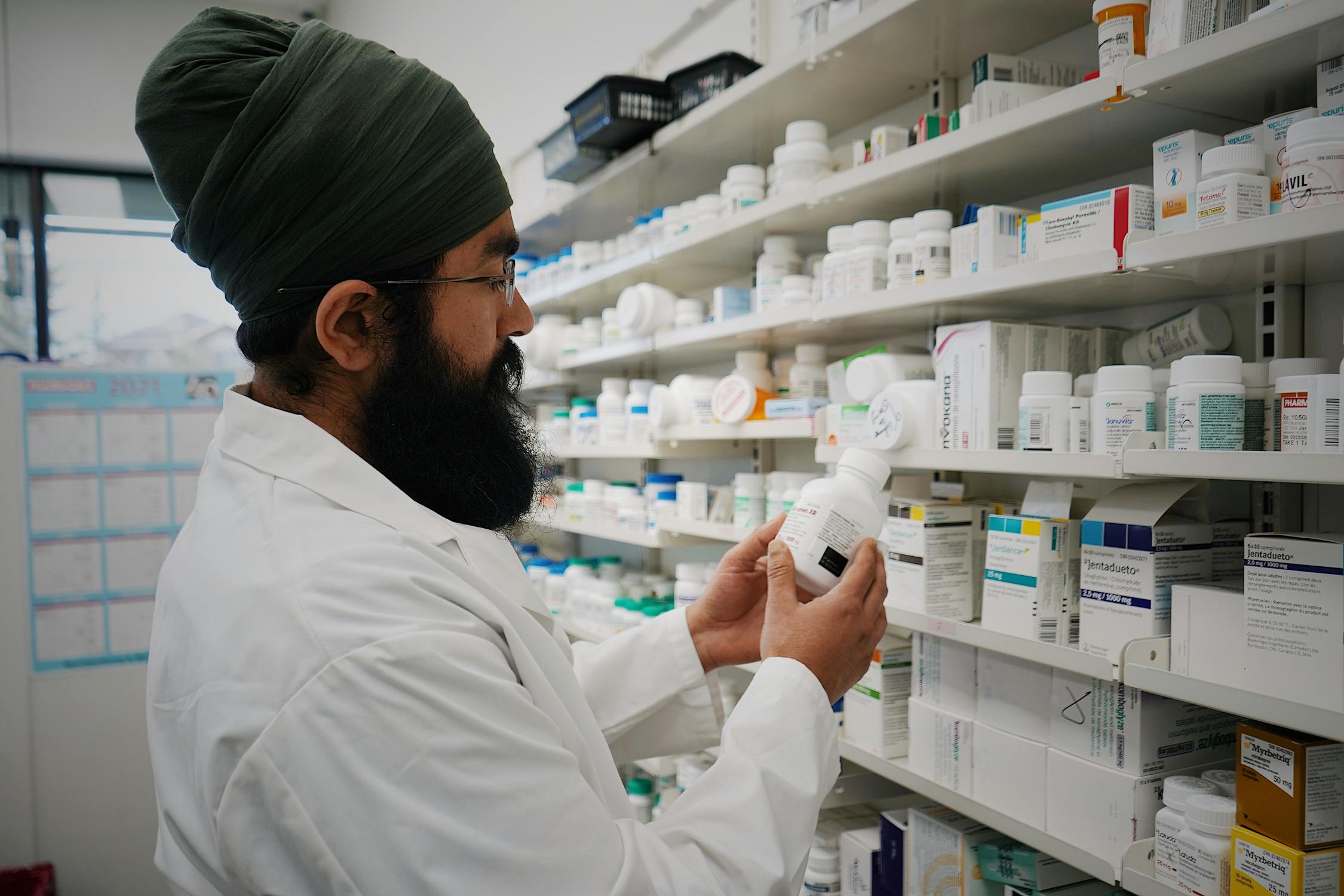 Pharmacist standing in front of organized medicine shelves